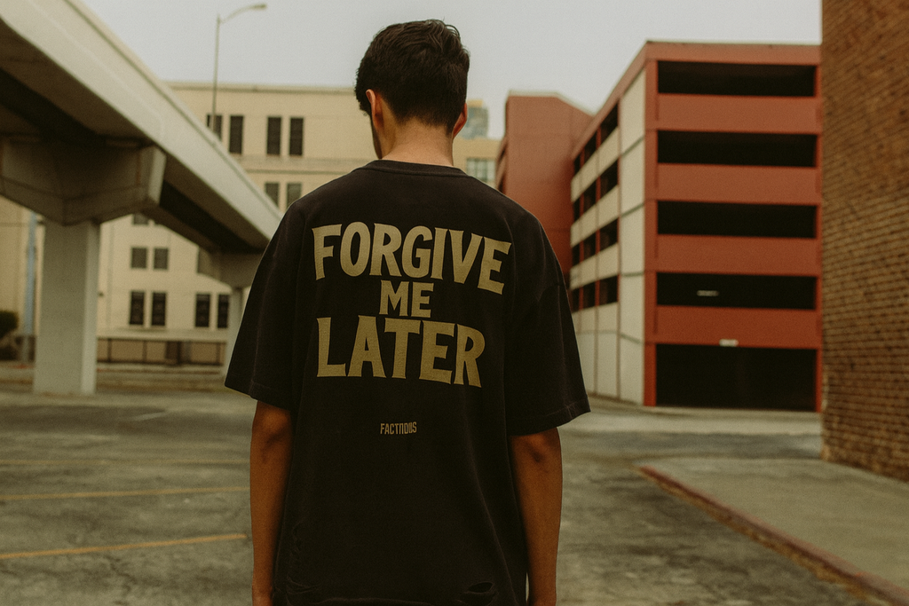Person wearing a black t-shirt with 'FORGIVE ME LATER' text in an urban setting